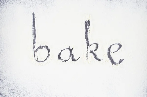 Flour.Inscription made by hand by sprinkled flour on a oven-tray — Stock Photo, Image