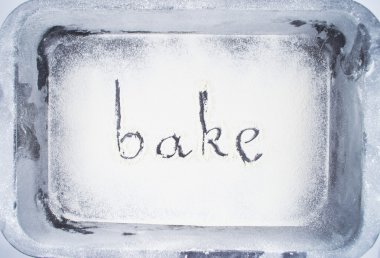 Flour.Inscription made by hand by sprinkled flour on a oven-tray clipart