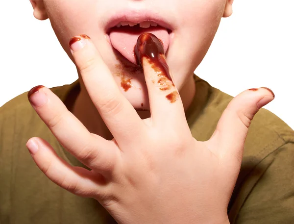 子供は指でチョコレート艶出しを舐める ストック写真