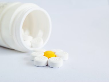 beyaz zemin üzerine hap şişesi