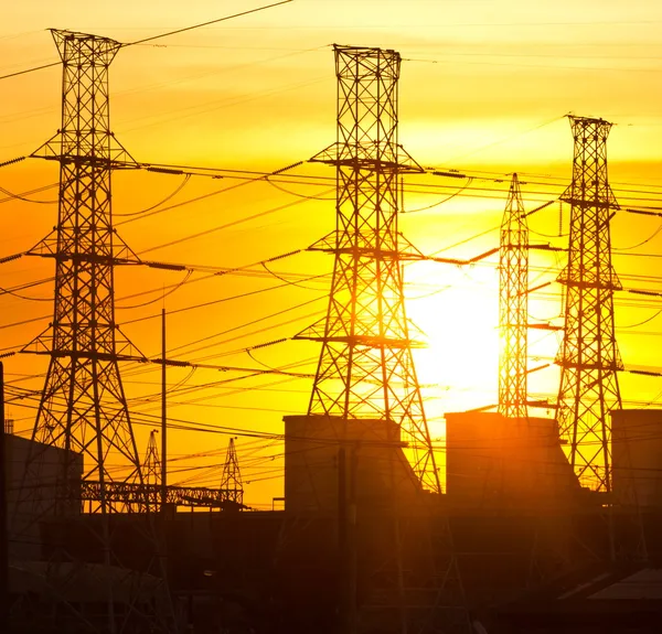 Elektrik hatları ve günbatımı santralde silüeti — Stok fotoğraf