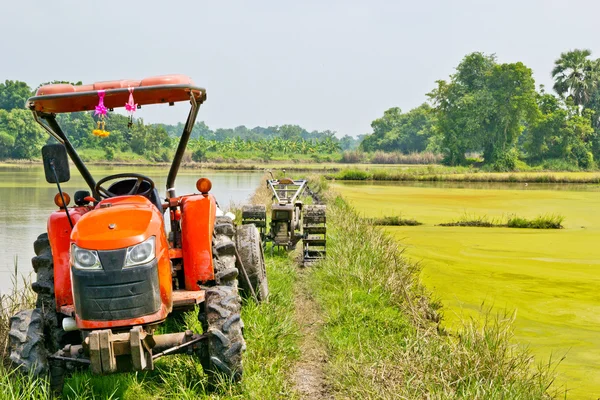 Grote trekker verzamelen hooiberg in het veld in een mooie blauwe zon — Stockfoto