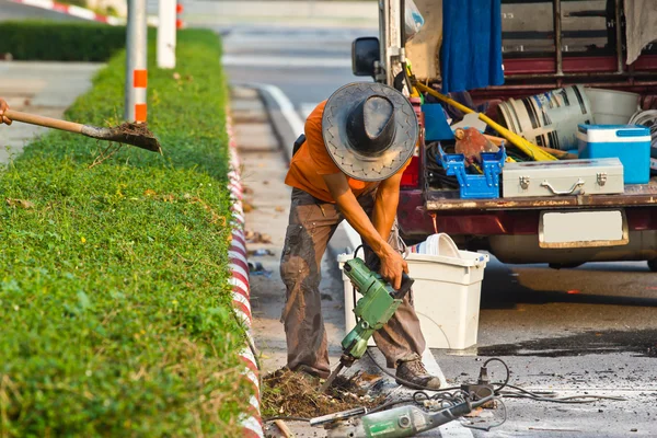 Дорожный рабочий на тротуаре с отбойным молотком, раскапывающим бетон — стоковое фото