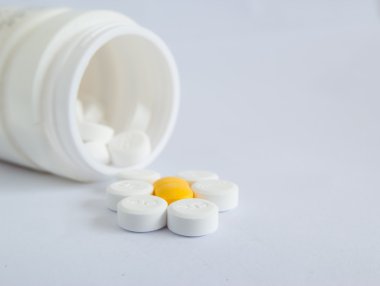 beyaz zemin üzerine hap şişesi