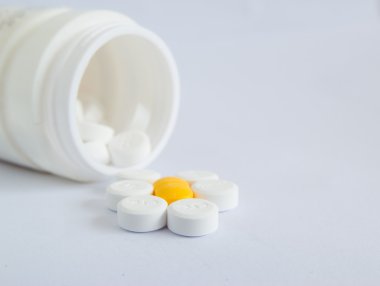 beyaz zemin üzerine hap şişesi