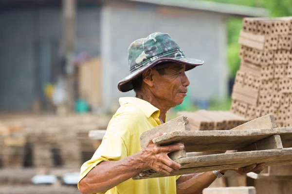 Obrero hombre levanta la madera de la producción de ladrillos en Tailandia —  Fotos de Stock