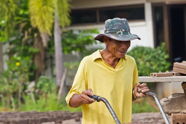 Mannen arbetare lyfter trät av produktionen av tegelstenar i thailand — Stockfoto