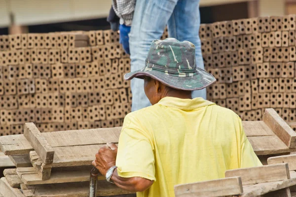 Mannen arbetare lyfter trät av produktionen av tegelstenar i thailand — Stockfoto