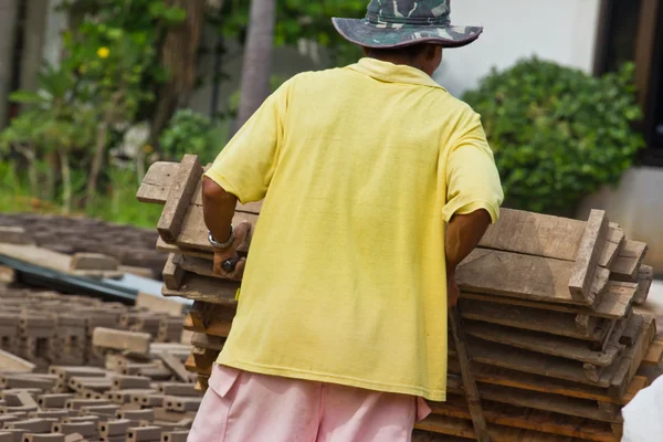 Mannen arbetare lyfter trät av produktionen av tegelstenar i thailand — Stockfoto