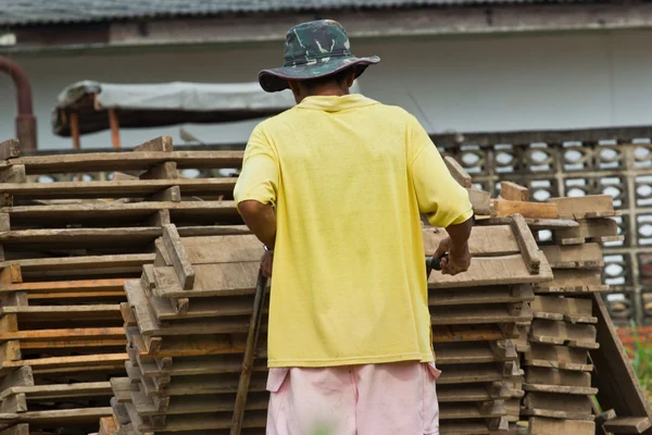 Homem trabalhador levanta a madeira de produção de tijolos na Tailândia — Fotografia de Stock