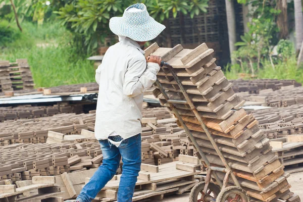 Mujer trabajadora levanta la madera de la producción de ladrillos en Tailandia — Foto de Stock