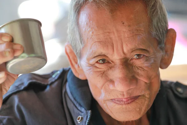 An aged cheerful old man holding a cup of coffee — Stock Photo, Image