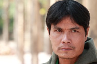 Genç yüzü sıradan bir adam duruyor.