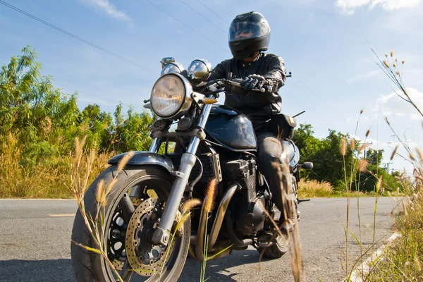 Motociclista na estrada contra o céu — Fotografia de Stock