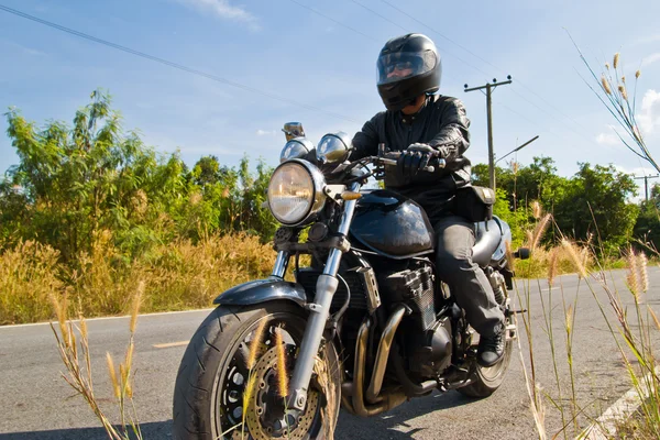 Vista de um homem com uma motocicleta em uma estrada de asfalto . — Fotografia de Stock