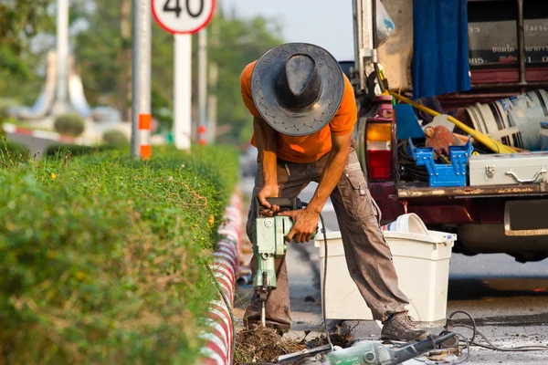 Trabajador de carretera en una acera con un martillo neumático desenterrando hormigón — Foto de Stock