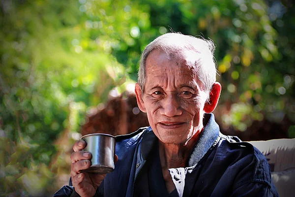 Un vieil homme gai et âgé tenant une tasse de café — Photo