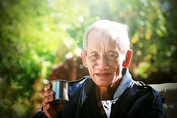 Un anciano alegre anciano sosteniendo una taza de café — Foto de Stock