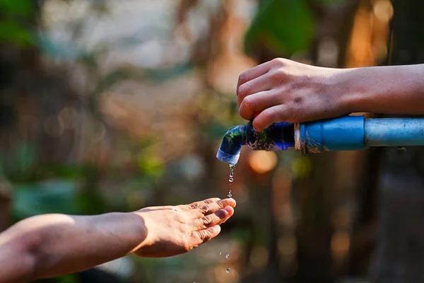 Hand hold outdoor water tap with tube — Stock Photo, Image