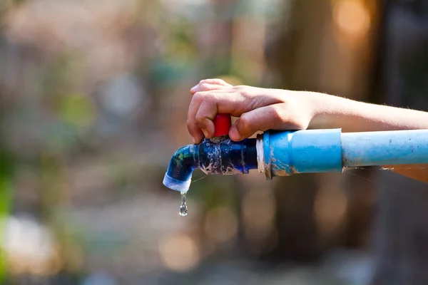 Mão mantenha torneira de água ao ar livre com tubo — Fotografia de Stock
