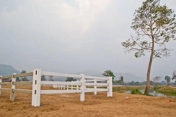 Cerca blanca en campo de la granja y cielo nublado — Foto de Stock