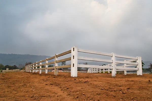 Cerca branca no campo de fazenda e céu nublado — Fotografia de Stock