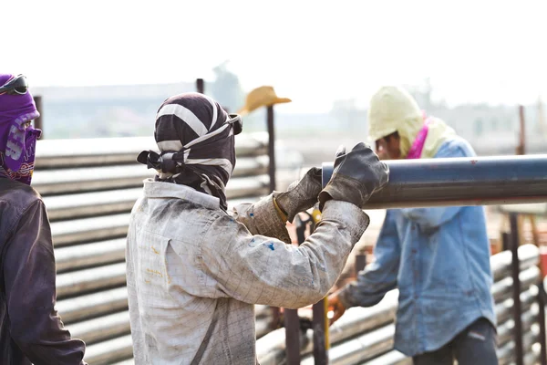 Trabajador de la construcción que lleva tubería de hierro — Foto de Stock