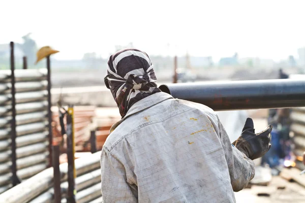 Construction worker carrying iron pipe — Stock Photo, Image