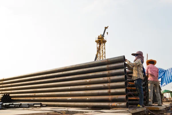 Construction worker carrying iron pipe — Stock Photo, Image