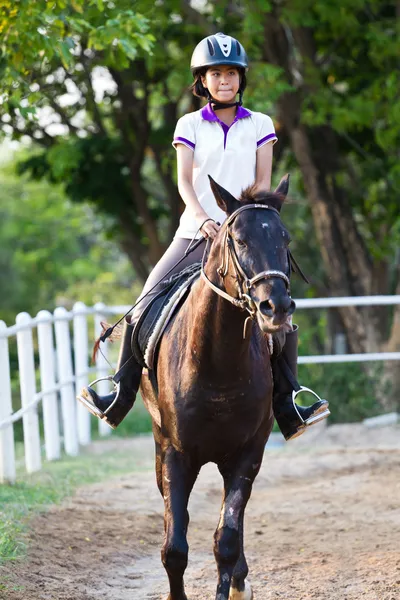 Beautiful teenager girl in brown dress riding brown horse — Stock Photo, Image