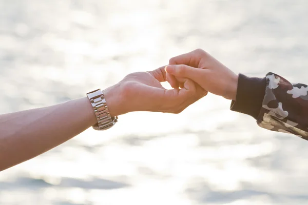 Молода пара в любові тримає руки, дивлячись на захід сонця — стокове фото