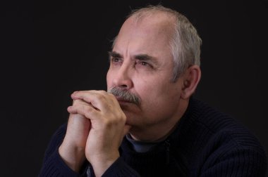 Siyah arka planda, düşünceli, olgun bir beyaz adamın güzel portresi.