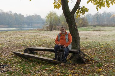 Sumskaya Oblastı, Ukrayna 'da sonbahar denizlerinde, ağacın altında dinlenen yalnız yaşlı turist.
