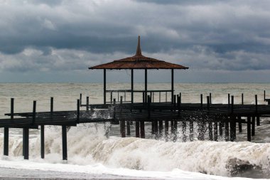 Fırtınalı bir denizin kıyısındaki eski metal iskele.