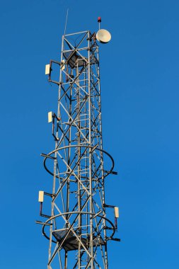 Telekomünikasyon kulesinde mavi gökyüzüne karşı güç ve sinyal kabloları ve hücresel antenler