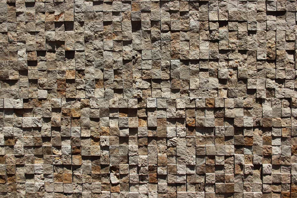 Relief mosaic wall of small stone cubes. Textured checkered background.
