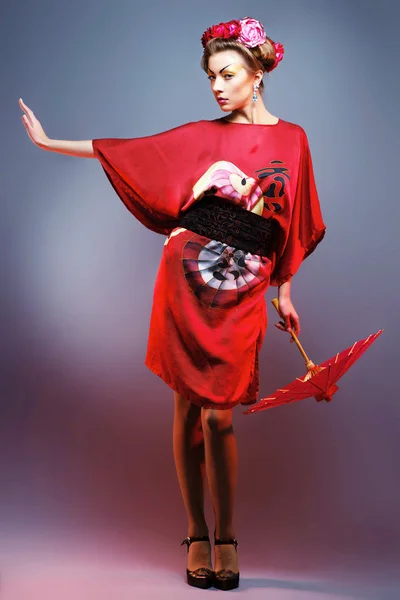 Fashion asian woman wearing traditional japanese red kimono with umbrella, studio shot. Geisha — Stock Photo, Image