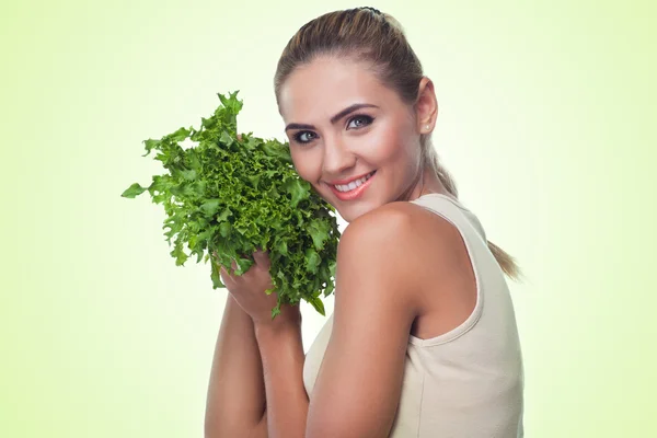 Glad ung kvinna med bunt örter (sallad) i händerna på vit ba — Stockfoto