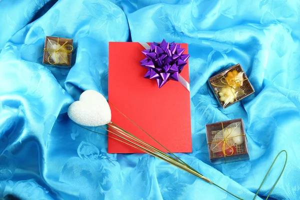 Rote Geschenkkarte mit Schleife auf blauem Satin — Stockfoto