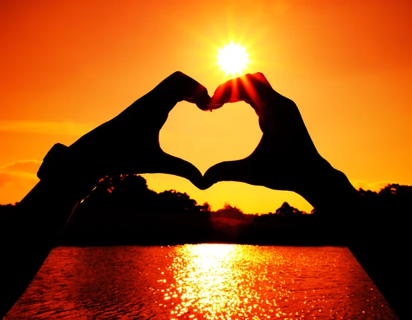 Srdce tvaru vyrobené rukama muž a žena na slunce — Stock fotografie