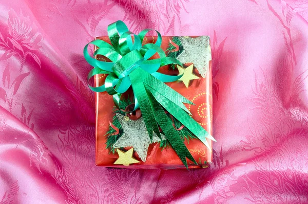 Red gift box with green ribbon on pink satin — Stock Photo, Image