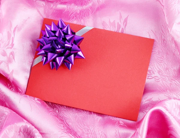 Red blank gift card with ribbon on pink satin — Stock Photo, Image