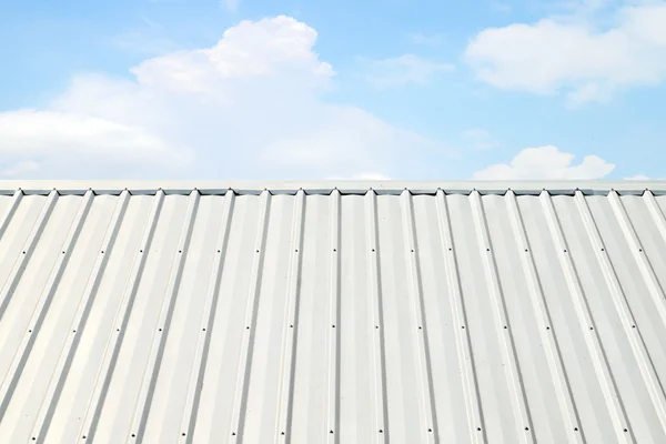Vlnité hliníkové střechy s modrou oblohou — Stock fotografie