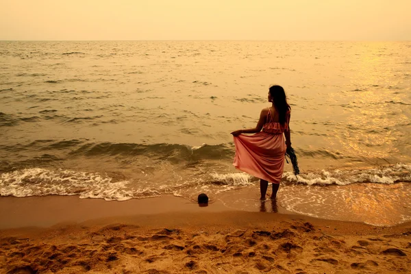 Mujer joven en la playa al atardecer — Foto de Stock