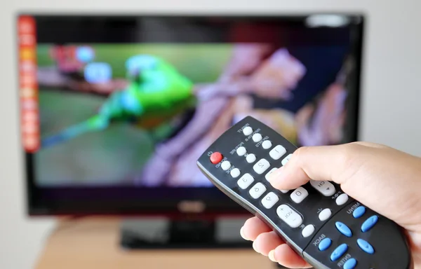 Mão apontando um controle remoto de TV para a televisão — Fotografia de Stock