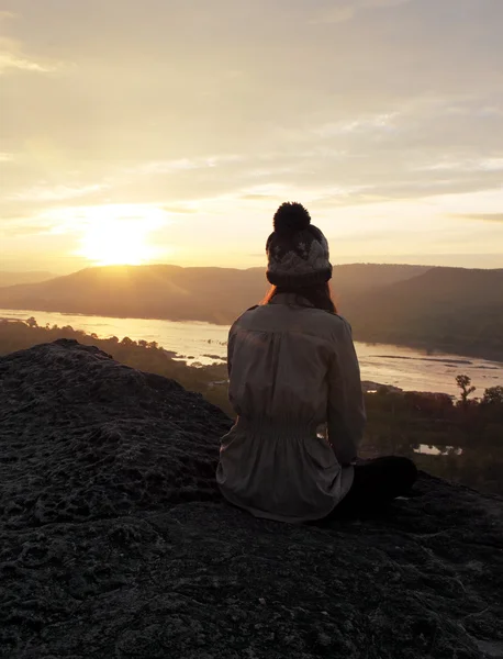 Woman sitting on cliff with sunrise — Stock Photo, Image