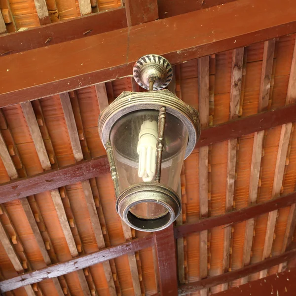 Vecchia lampada appesa al soffitto sotto un baldacchino di legno — Foto Stock