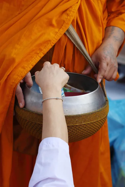 Hand legte Speisopfer in eine buddhistische Almosenschale — Stockfoto