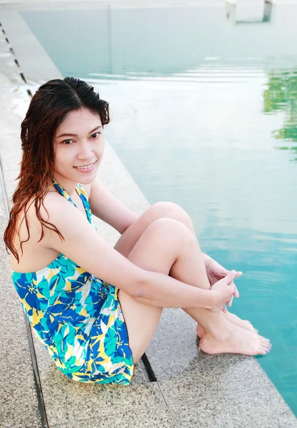 Mulher sentada à beira de uma piscina — Fotografia de Stock