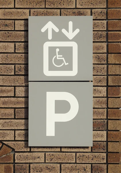 Señal de aparcamiento para discapacitados en la pared de ladrillo —  Fotos de Stock